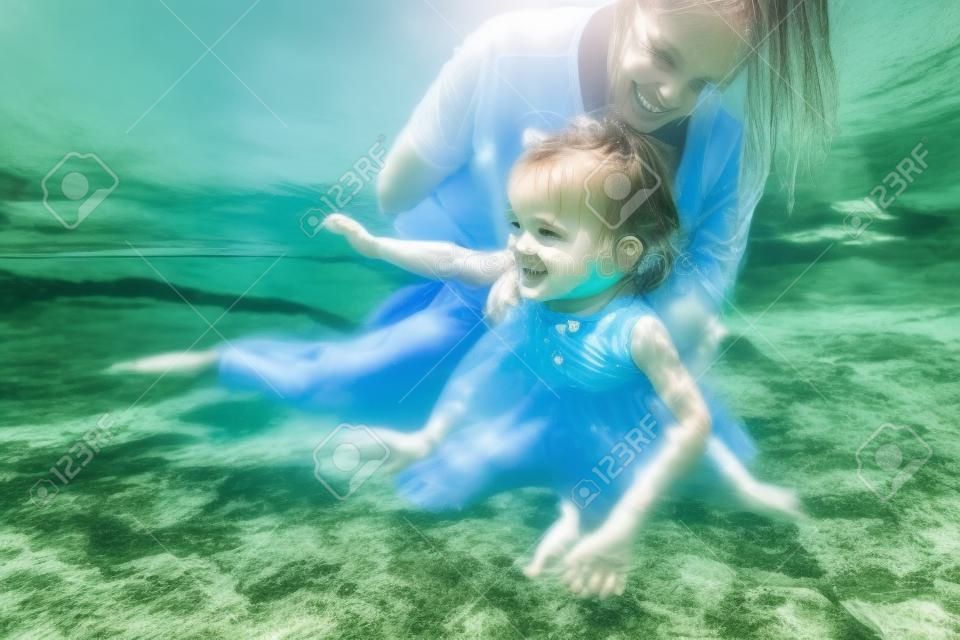 happy mother and daughter swimming together in river