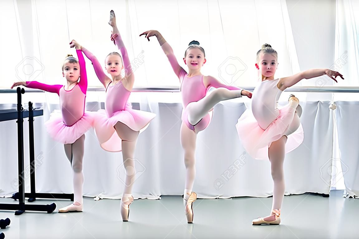 beautiful little ballet dancers exercising and looking at camera in ballet school