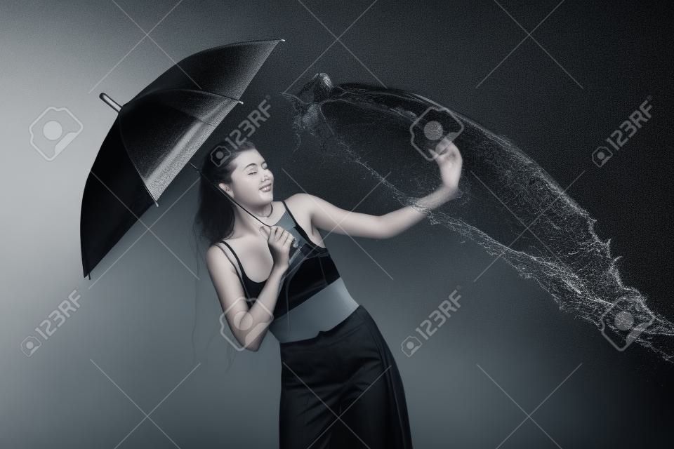 블랙에 절연 물으로 swilled 우산을 가진 젊은 감정적 인 여자