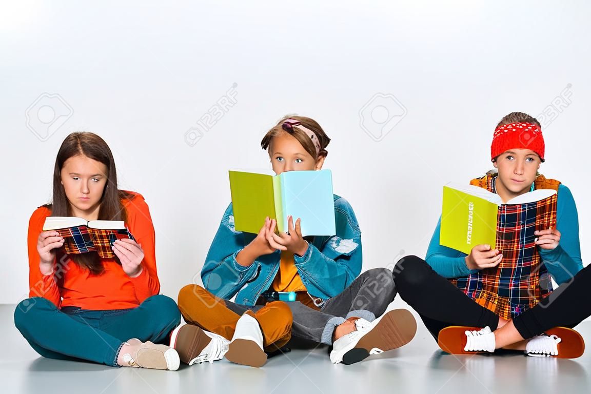 jóvenes estudiantes sentados con longboard y sosteniendo libros