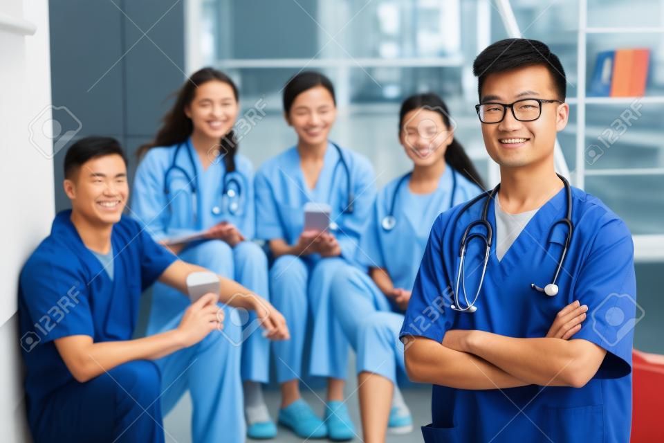 의과대학에서 백인 교사와 학생들 앞에 서 있는 아시아 남자