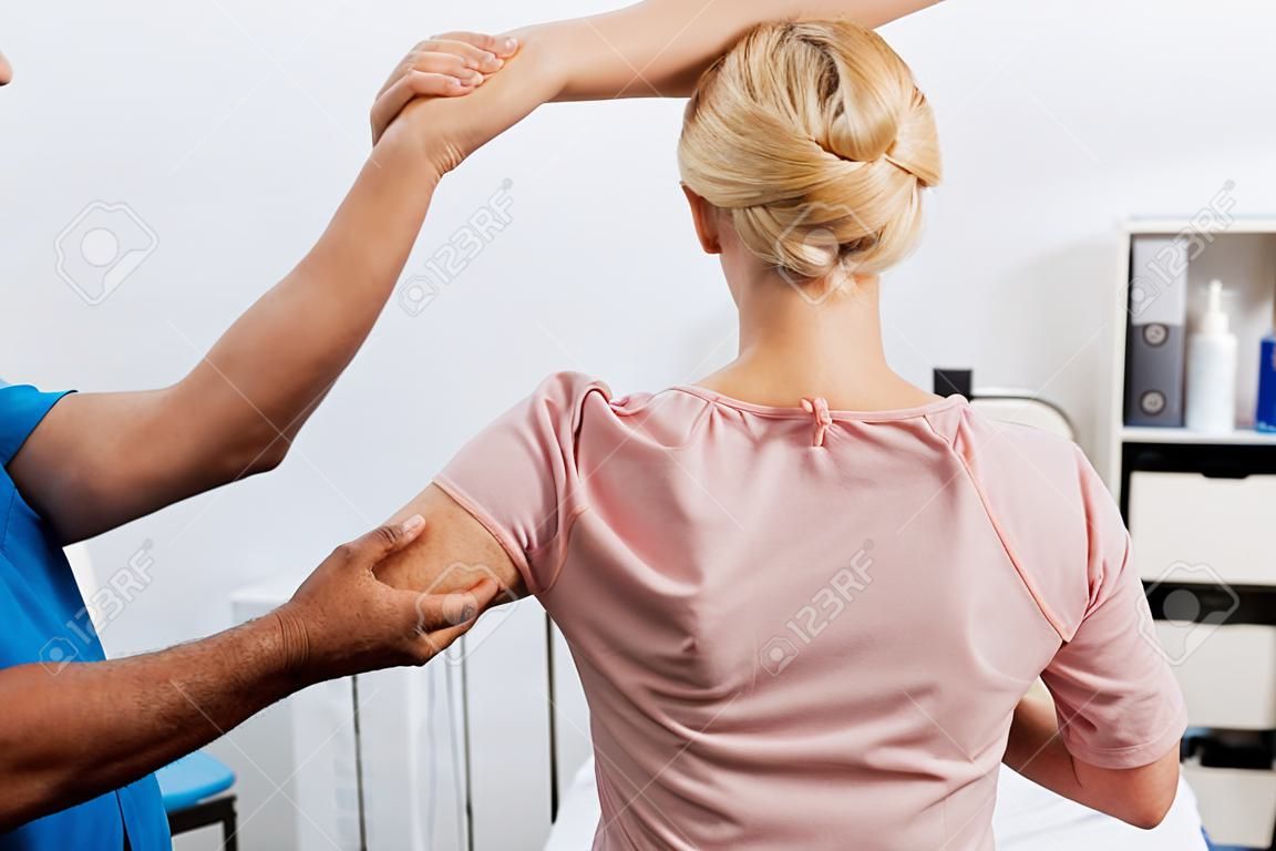 Cropped shot of physiotherapist doing massage to woman on massage table in hospital