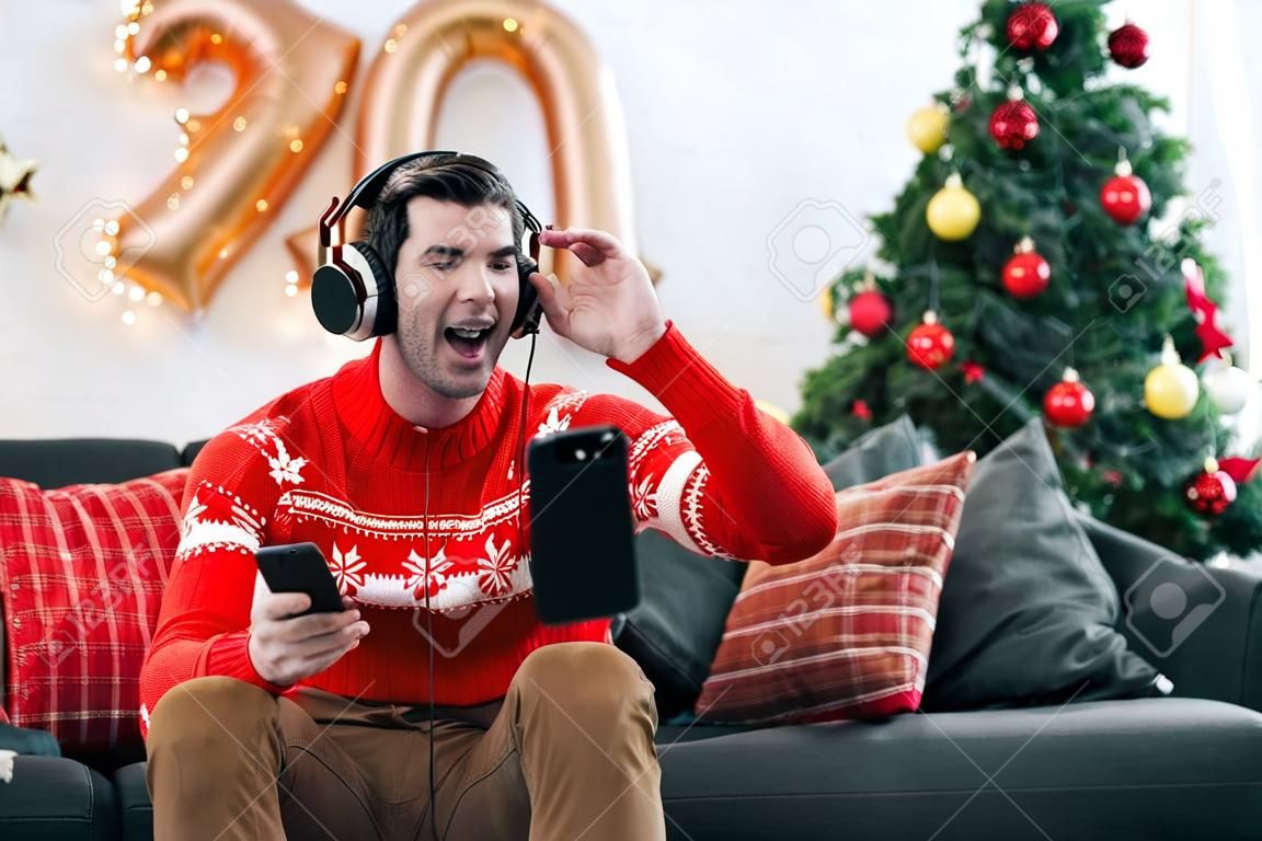Excited man listening music with headphones and smartphone on christmas eve