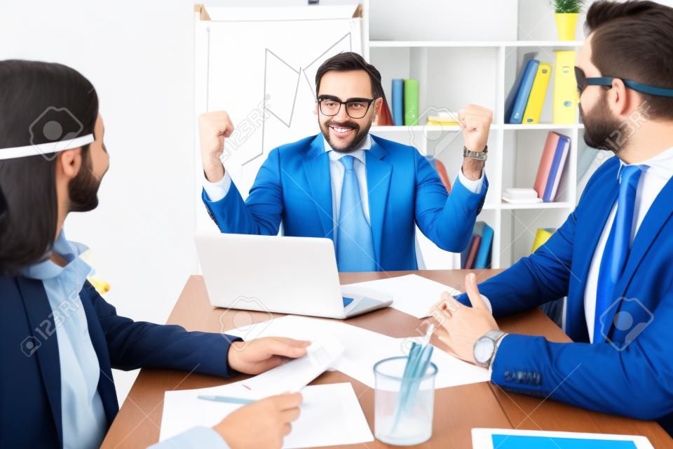 super businessman showing yes gesture to colleagues in office