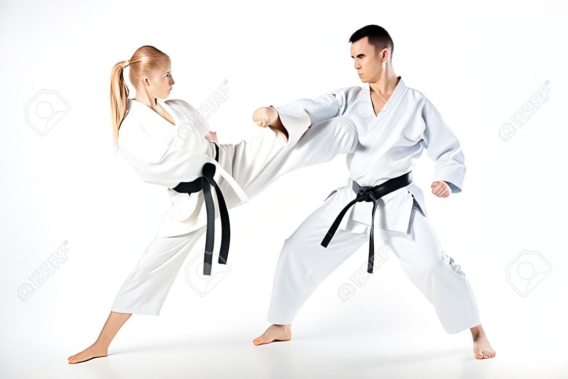 female karate fighter kicking male partner isolated on white