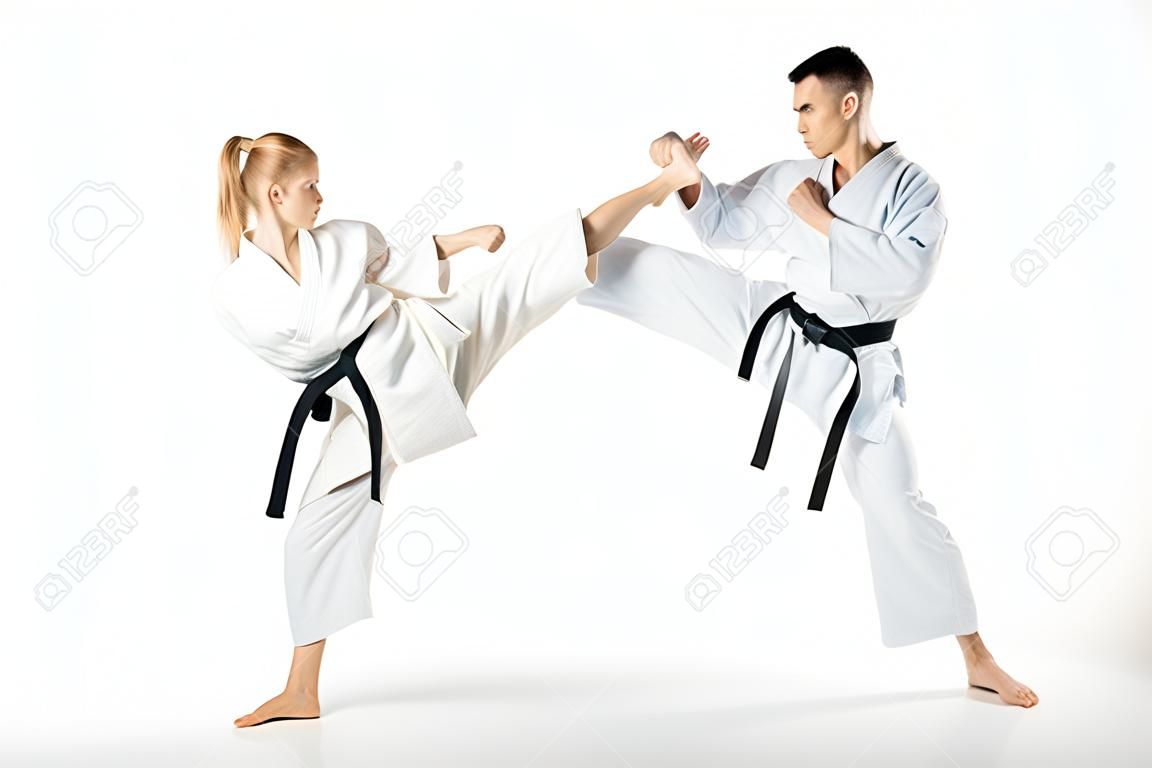 Luchador de karate femenino pateando compañero masculino aislado en blanco
