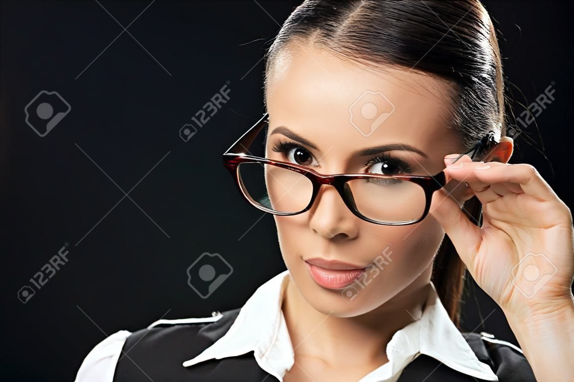 Porträt einer schönen Geschäftsfrau mit Brille, die in die Kamera schaut, isoliert auf schwarz