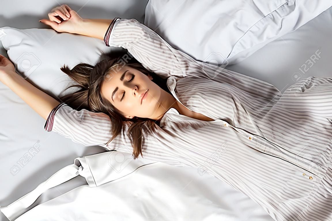 top view of young attractive woman in pajamas sleeping on bed in the morning