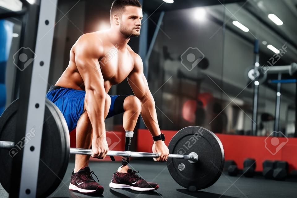 An attractive young sportsman with artificial leg working out with barbell at gym