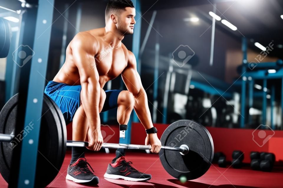 An attractive young sportsman with artificial leg working out with barbell at gym