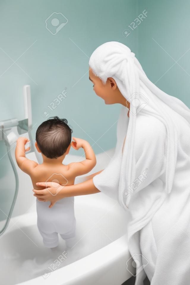 Madre con hijo de lavado de pelo largo en el baño blanco