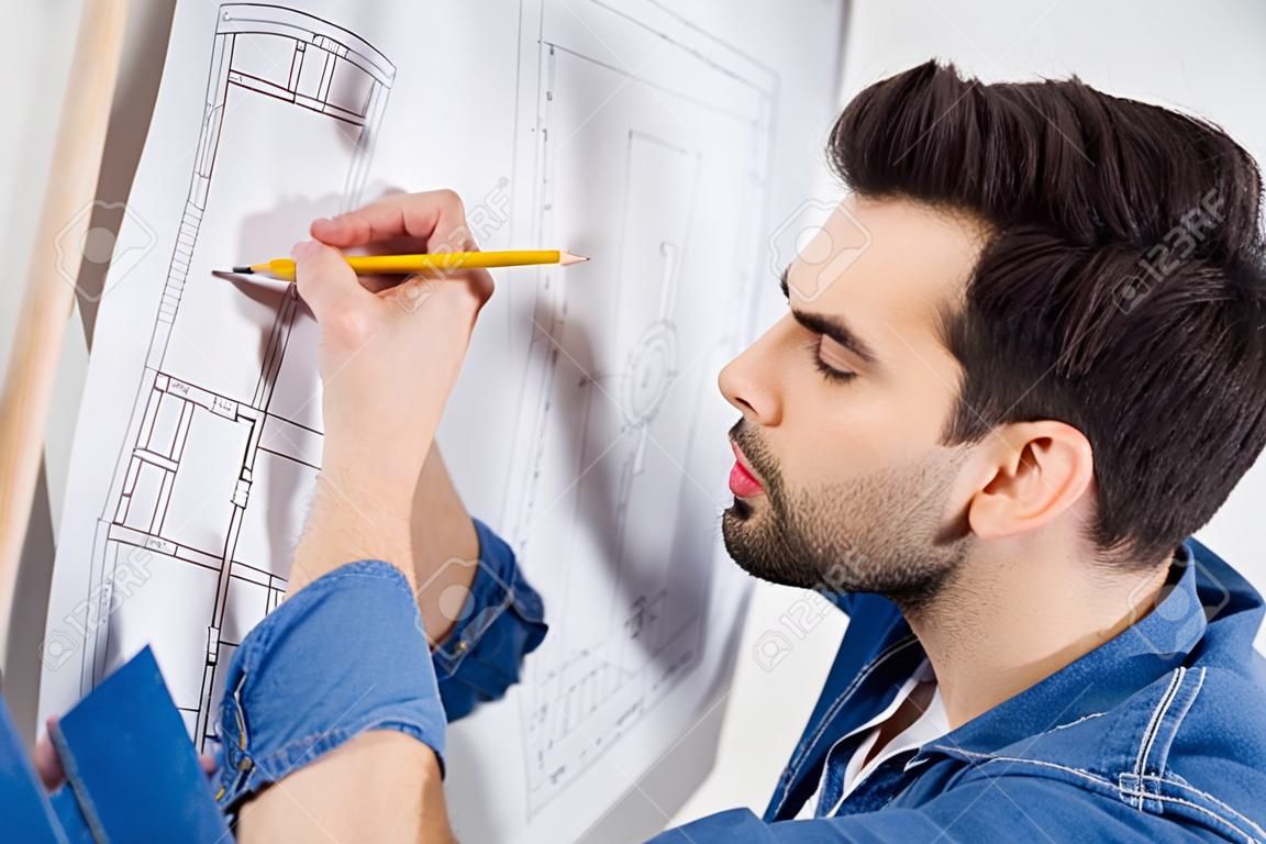 handsome architect writing on blueprint on white