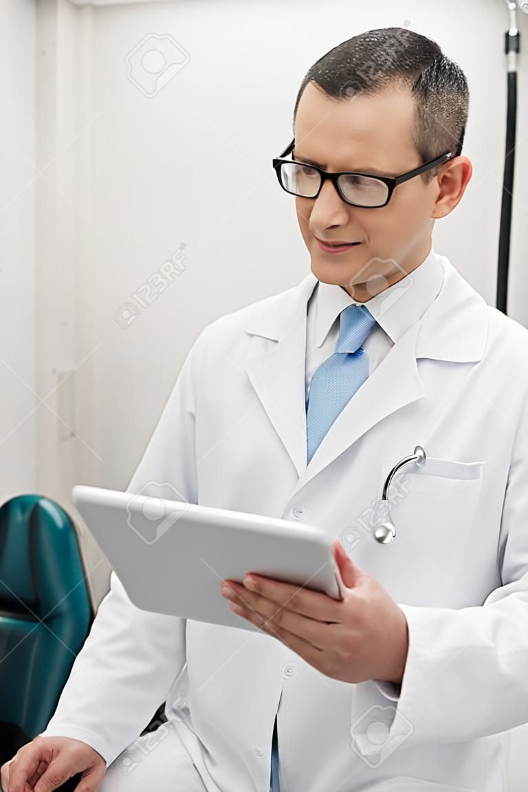 retrato de médico con bata blanca usando tableta digital en la clínica