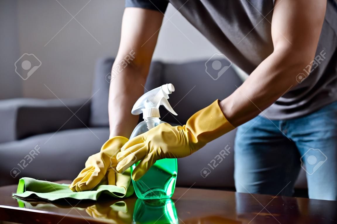 immagine ritagliata del tavolo per la pulizia dell'uomo in soggiorno con flacone spray e straccio