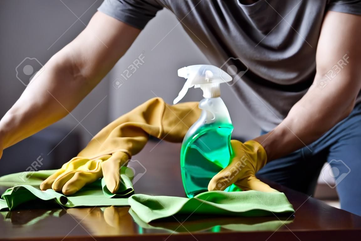 immagine ritagliata del tavolo per la pulizia dell'uomo in soggiorno con flacone spray e straccio