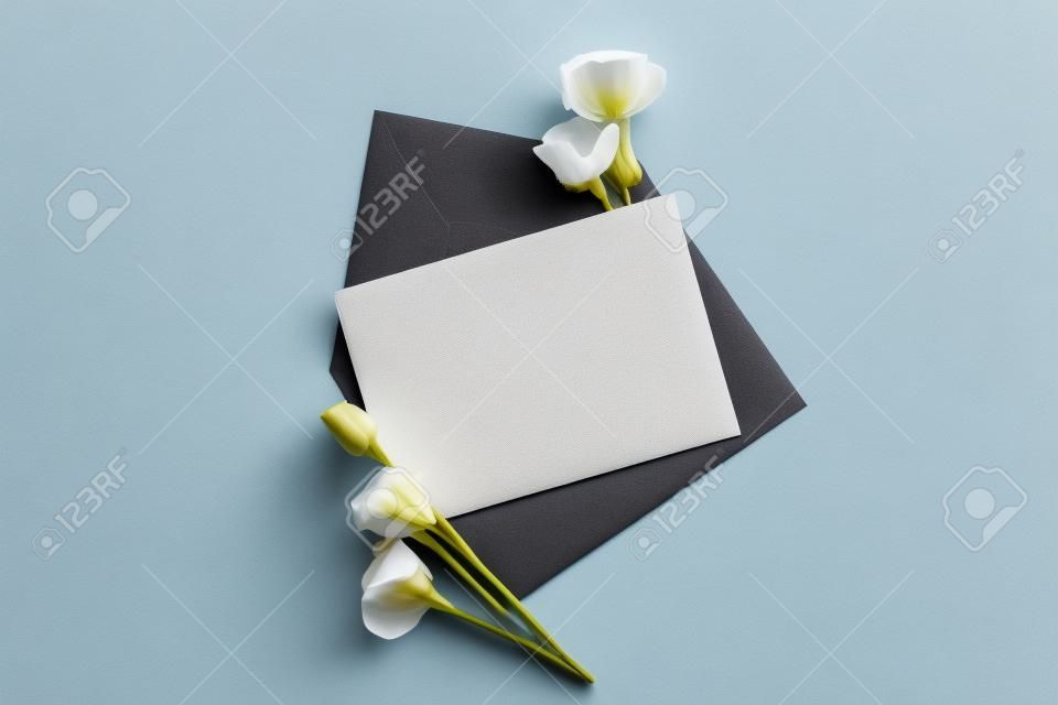 top view of eustoma and envelope with empty card on grey background