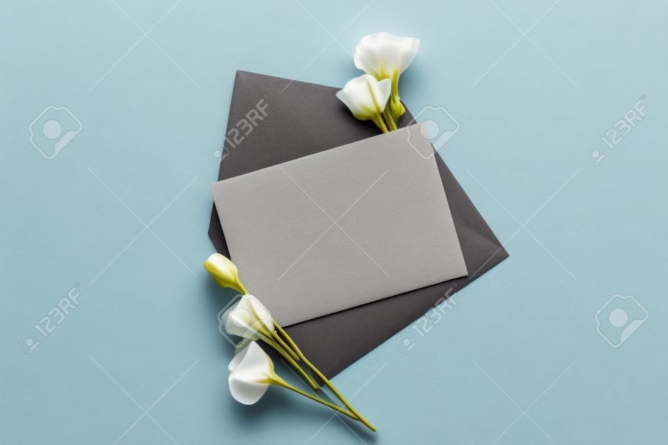 top view of eustoma and envelope with empty card on grey background