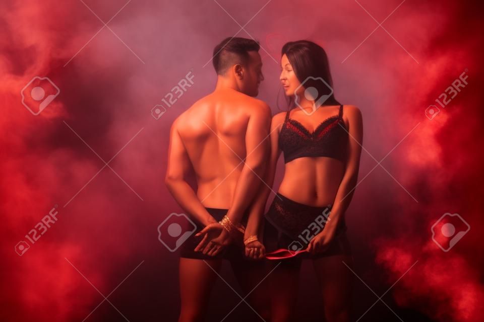 bella coppia appassionata con nastro rosso in una stanza fumosa