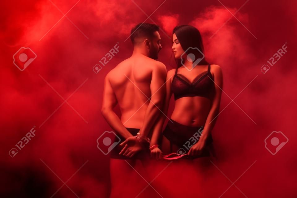 beautiful passionate couple with red ribbon in smoky room