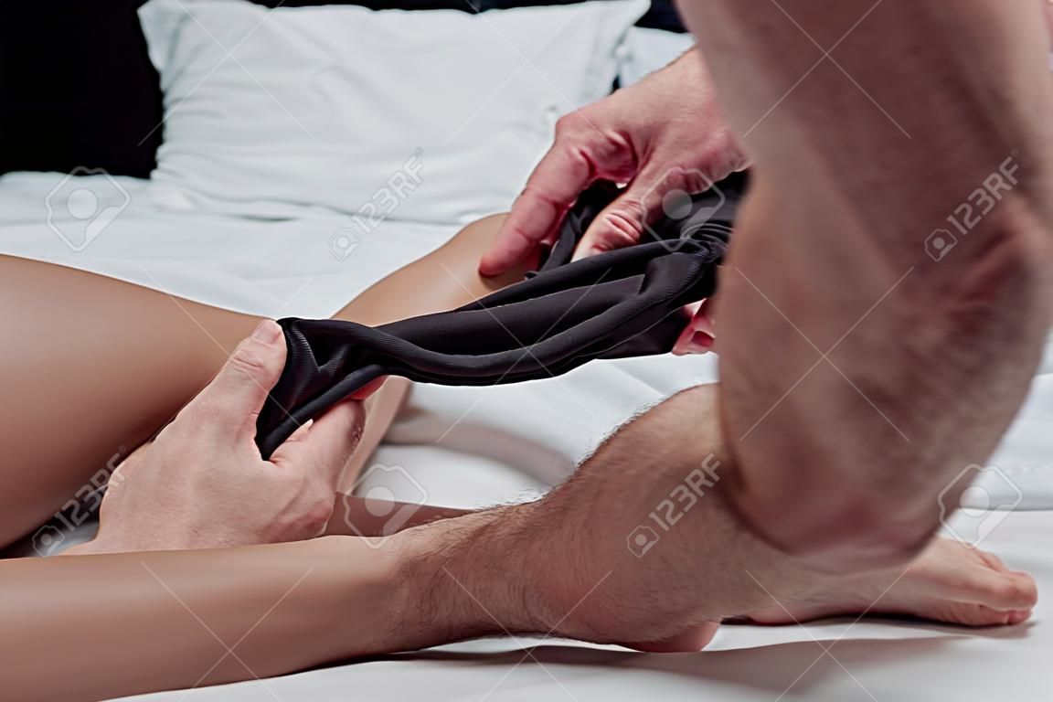 Częściowy widok mężczyzny rozbierającego kobietę w łóżku