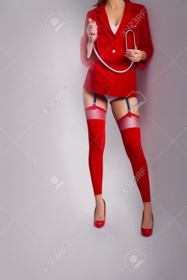 Ausgeschnittene Ansicht einer Krankenschwester in Kurzmantel, Strümpfen und roten Schuhen mit Stethoskop auf weißem Hintergrund