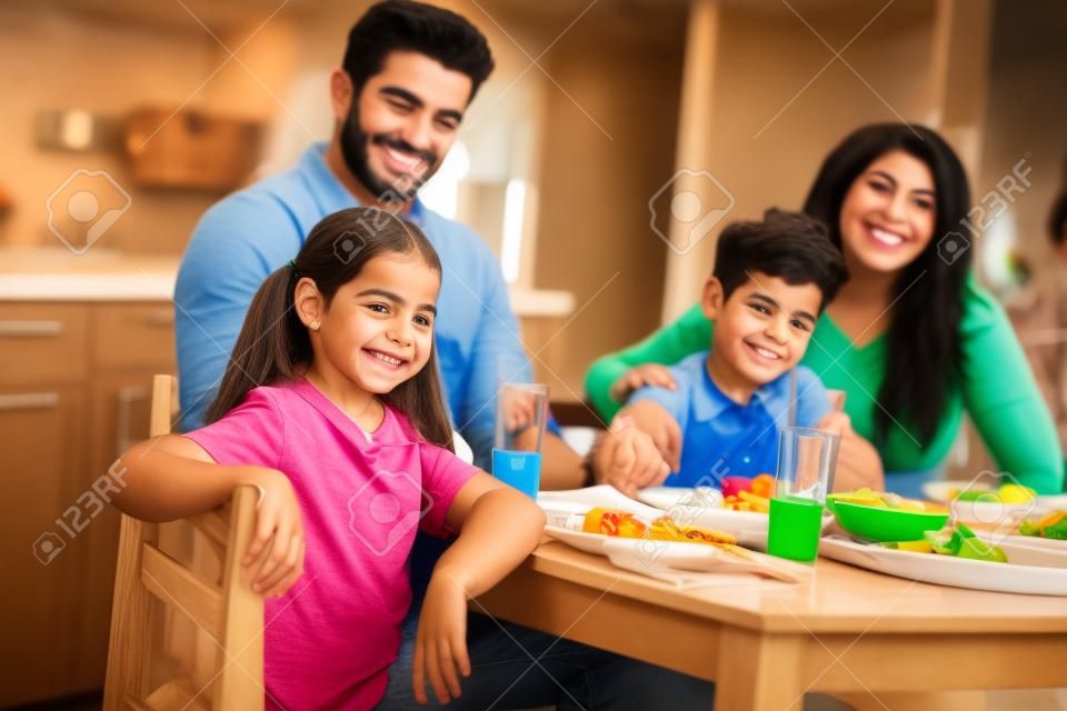selectieve focus van gelukkig Spaans kind glimlachen terwijl kijken naar camera met latino familie op achtergrond