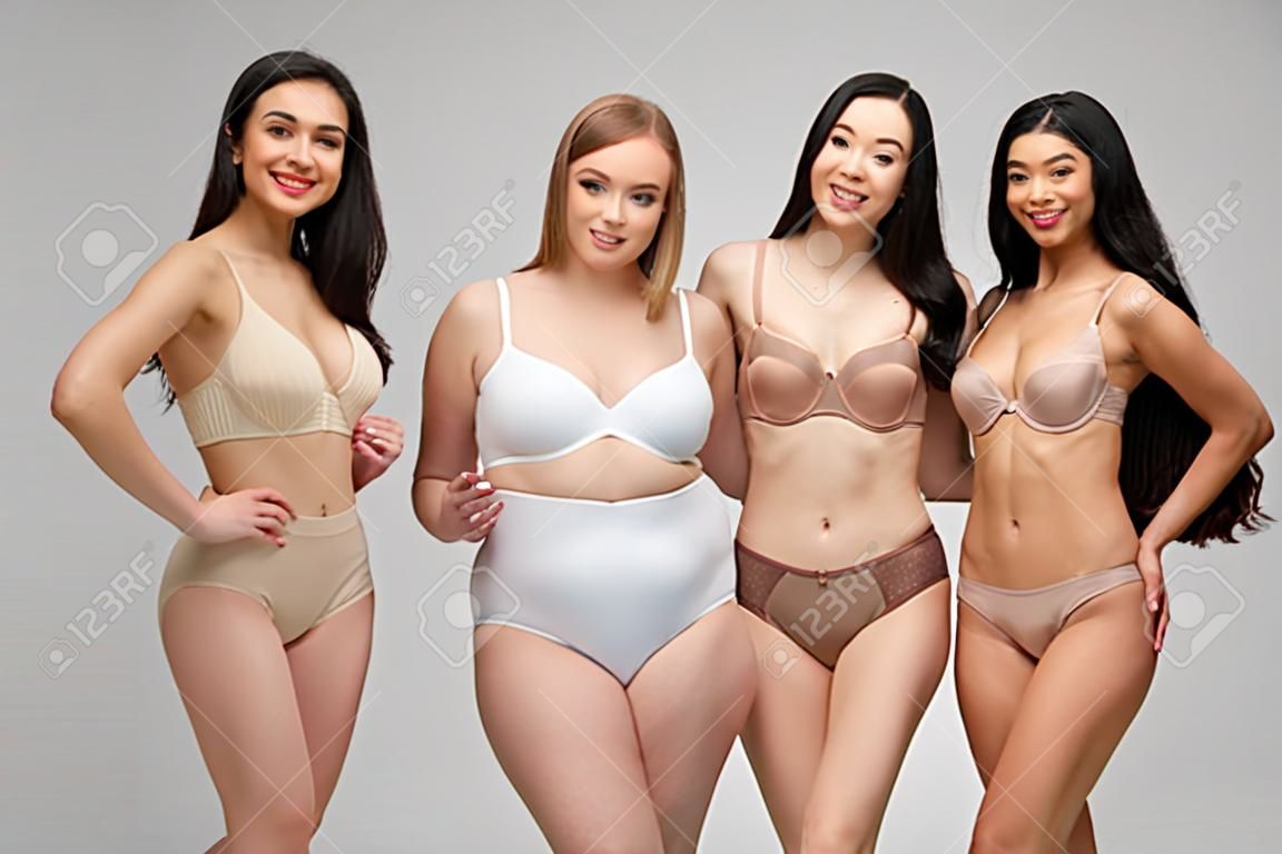 속옷을 입은 5명의 아름다운 다문화 소녀들이 카메라를 보고 회색, 신체 양성 개념에 고립되어 웃고
