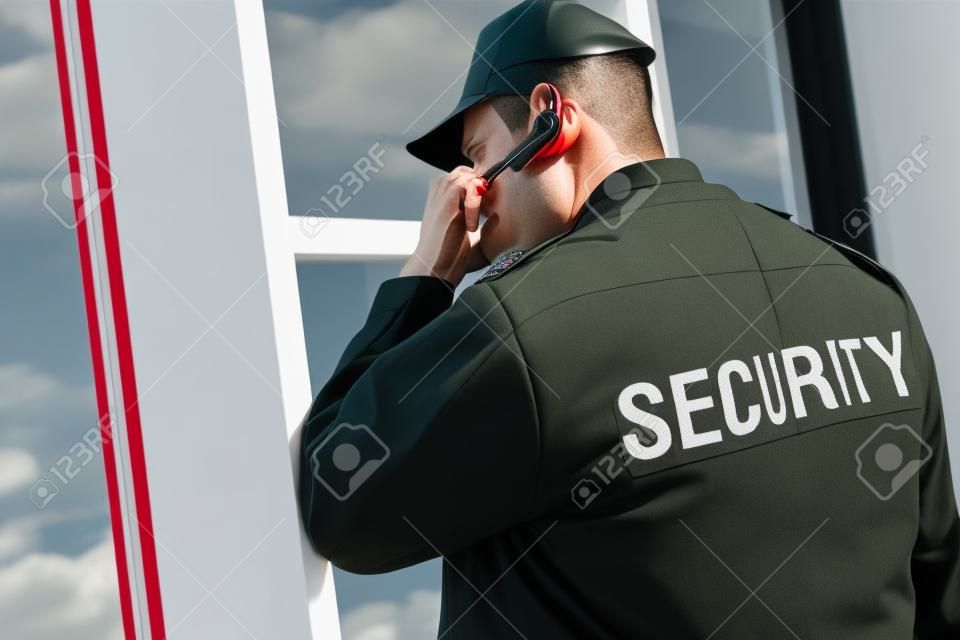 rear view of guard in uniform using earphone