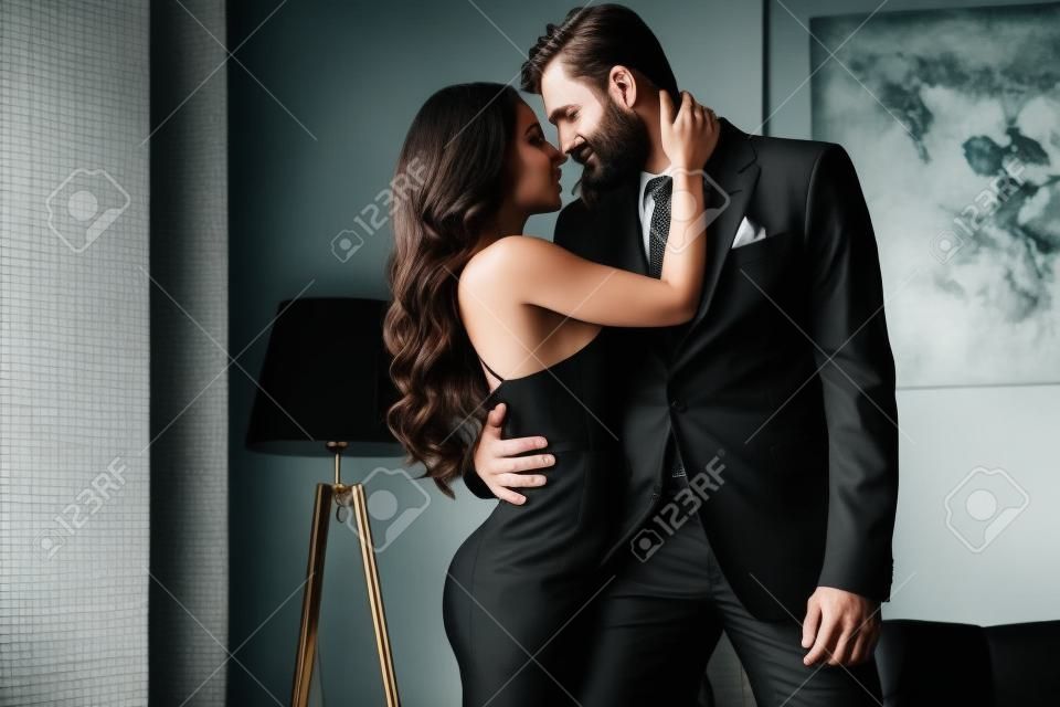 attractive woman in black dress hugging with passionate man in suit