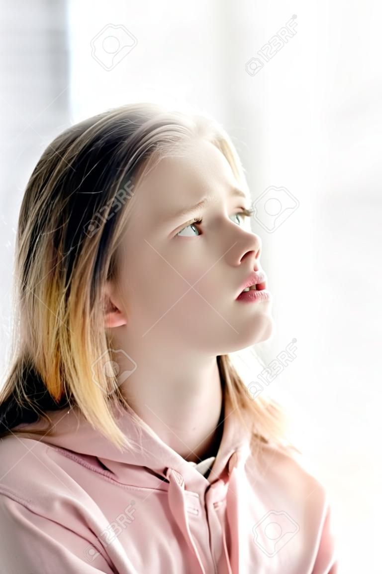 Pensive tiener kind in roze hoodie wegkijken