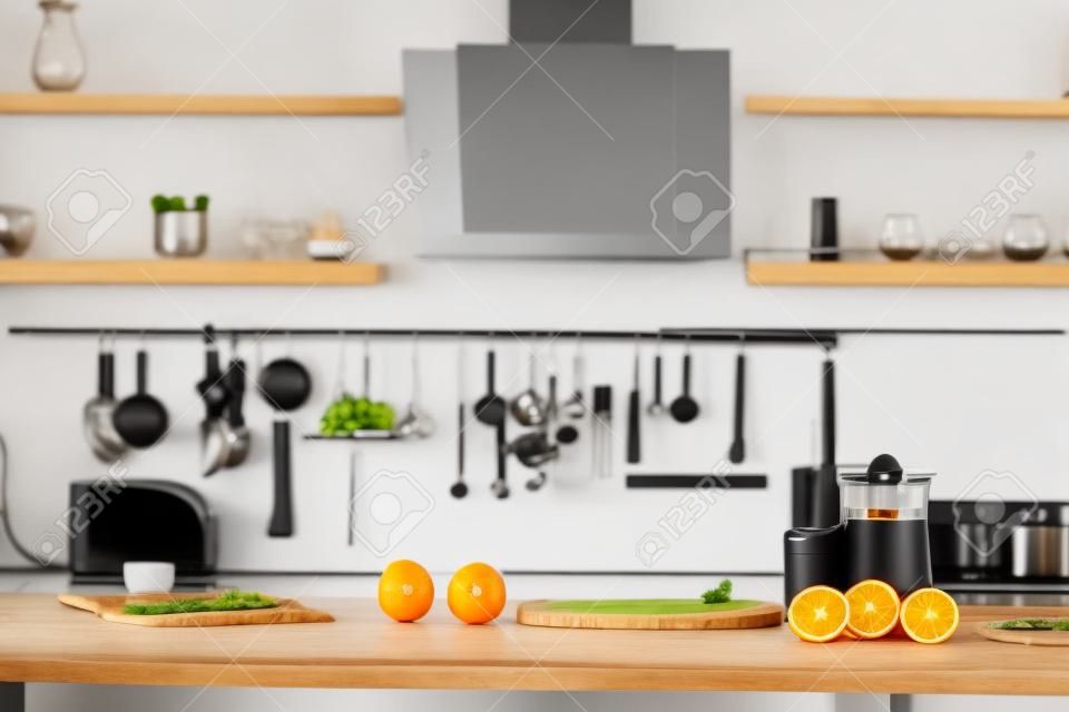 Modern kitchen with juicer, glass and tasty organic oranges on wooden table