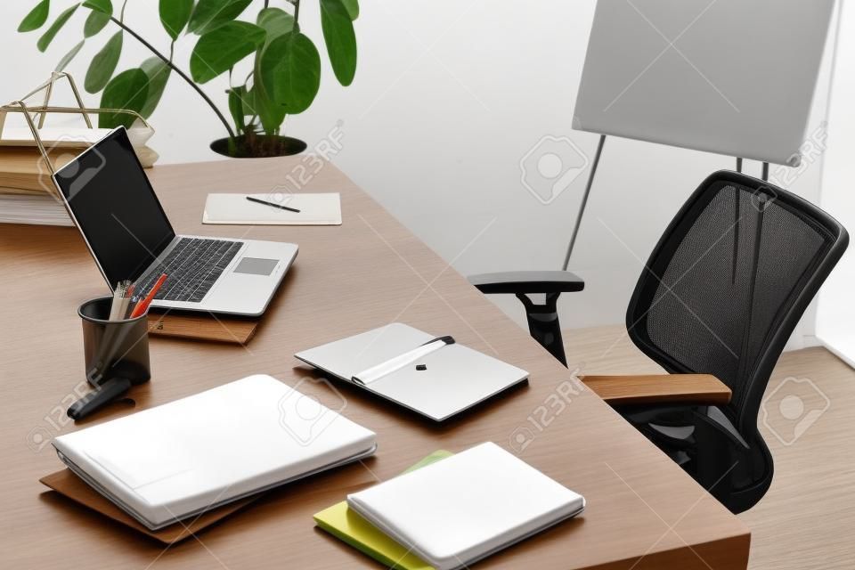 Modern office with laptop, smartphone, resume and blank notebook on desk