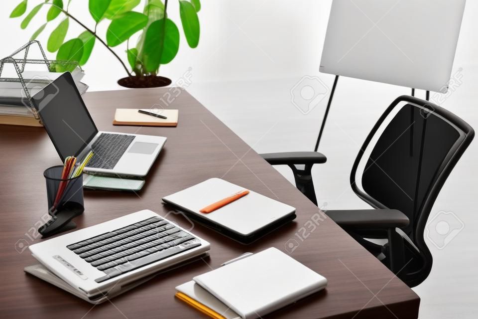 Modern office with laptop, smartphone, resume and blank notebook on desk