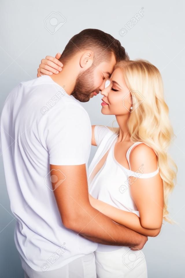 Handsome man with closed eyes hugging blonde girl on white background