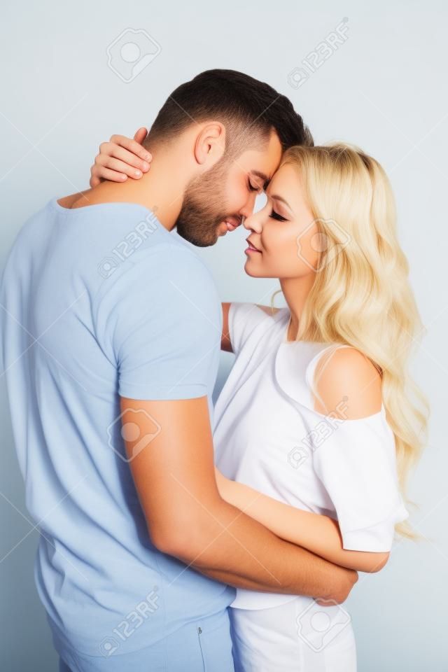 Handsome man with closed eyes hugging blonde girl on white background