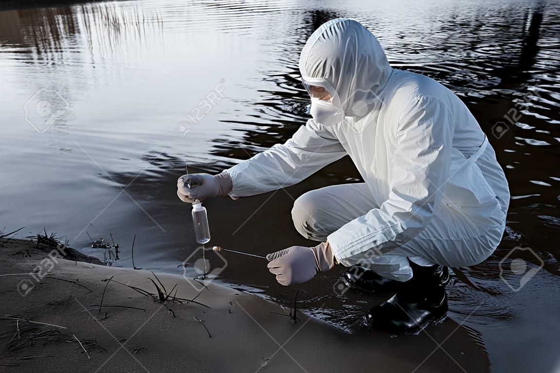 川で水のサンプルを取る保護衣装と呼吸器の水検査官