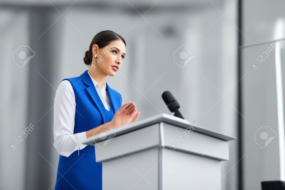 aantrekkelijke zakenvrouw staan en wegkijken tijdens conferentie in conferentiezaal