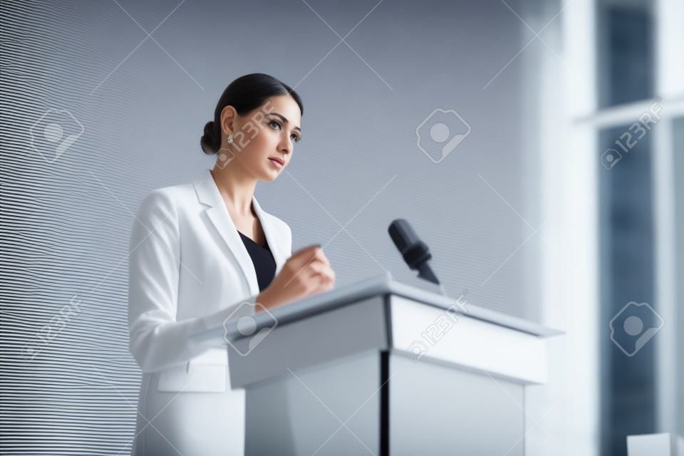 aantrekkelijke zakenvrouw staan en wegkijken tijdens conferentie in conferentiezaal