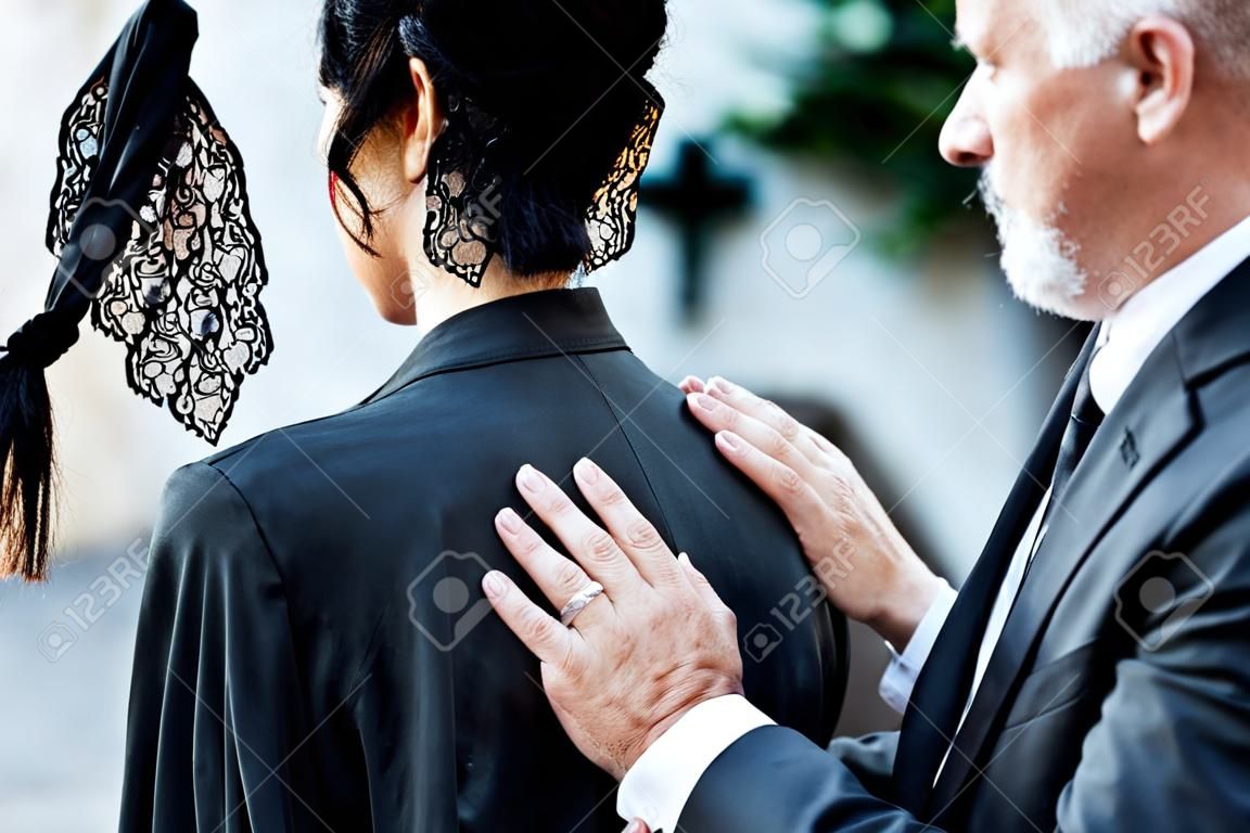 przycięty widok mężczyzny dotykającego kobiety na pogrzebie