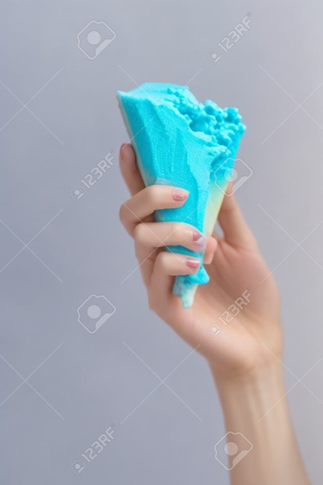 partial view of woman holding delicious melted blue ice cream in crispy waffle cone isolated on yellow
