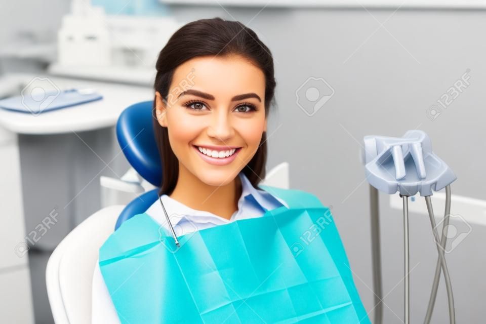 belle femme assise et souriante dans une clinique dentaire