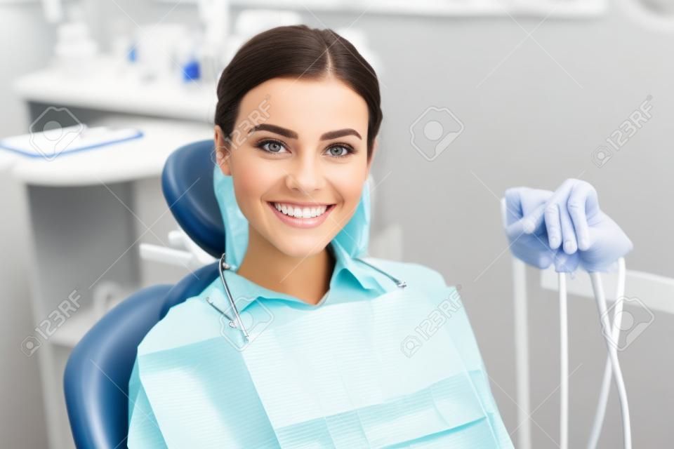 Bella mujer sentada y sonriendo en la clínica dental