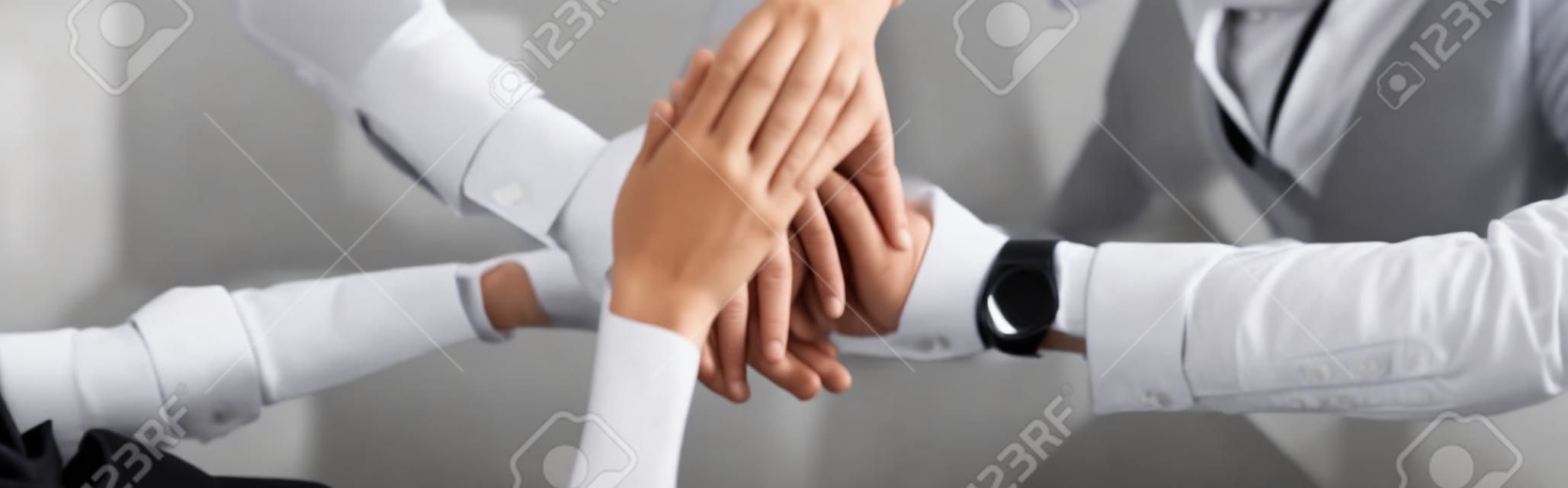 panoramic shot of businesswoman and businessmen putting hands together