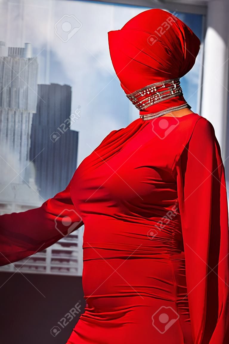 stylish woman in red dress and balaclava on city background 
