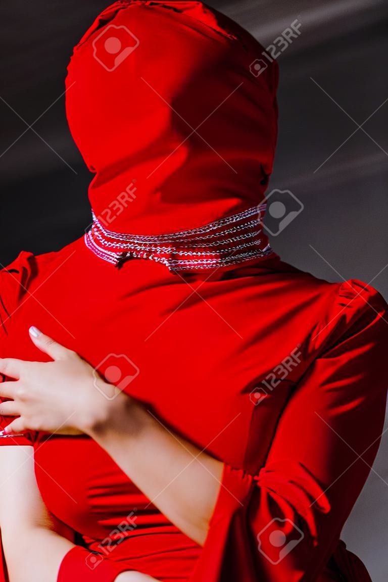 low angle view of stylish woman in red dress and balaclava isolated on grey