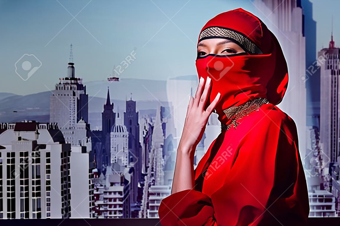 stylish woman in red dress and balaclava on city background