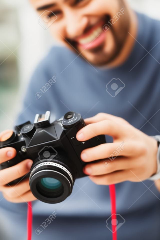 selective focus of smiling bi-racial man holding digital camera