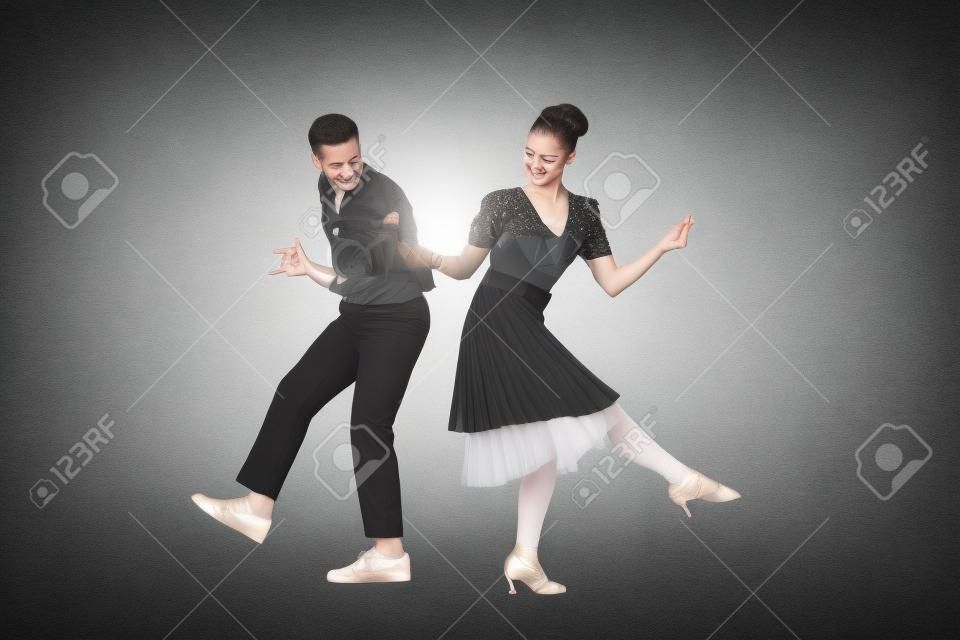 young dancers holding hands while dancing boogie-woogie on grey background