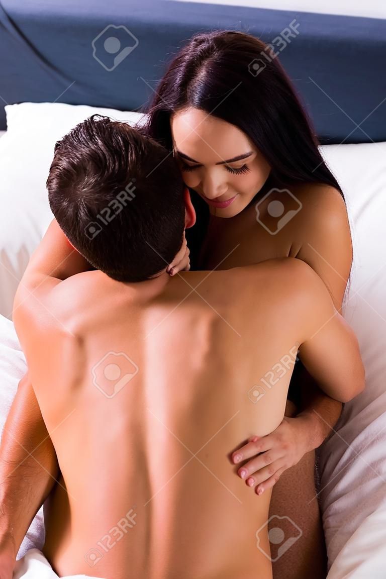 high angle view of smiling brunette woman hugging shirtless man on bed
