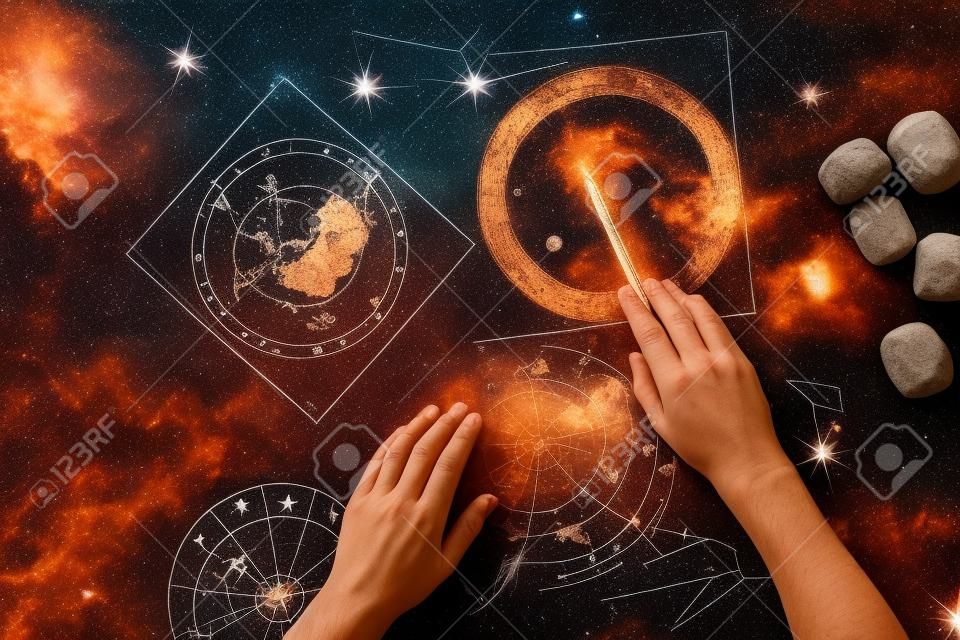 top view of cropped astrologer pointing at celestial map near clay runes
